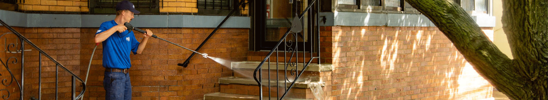 A Perfect Power Wash employee washes concrete and brick steps